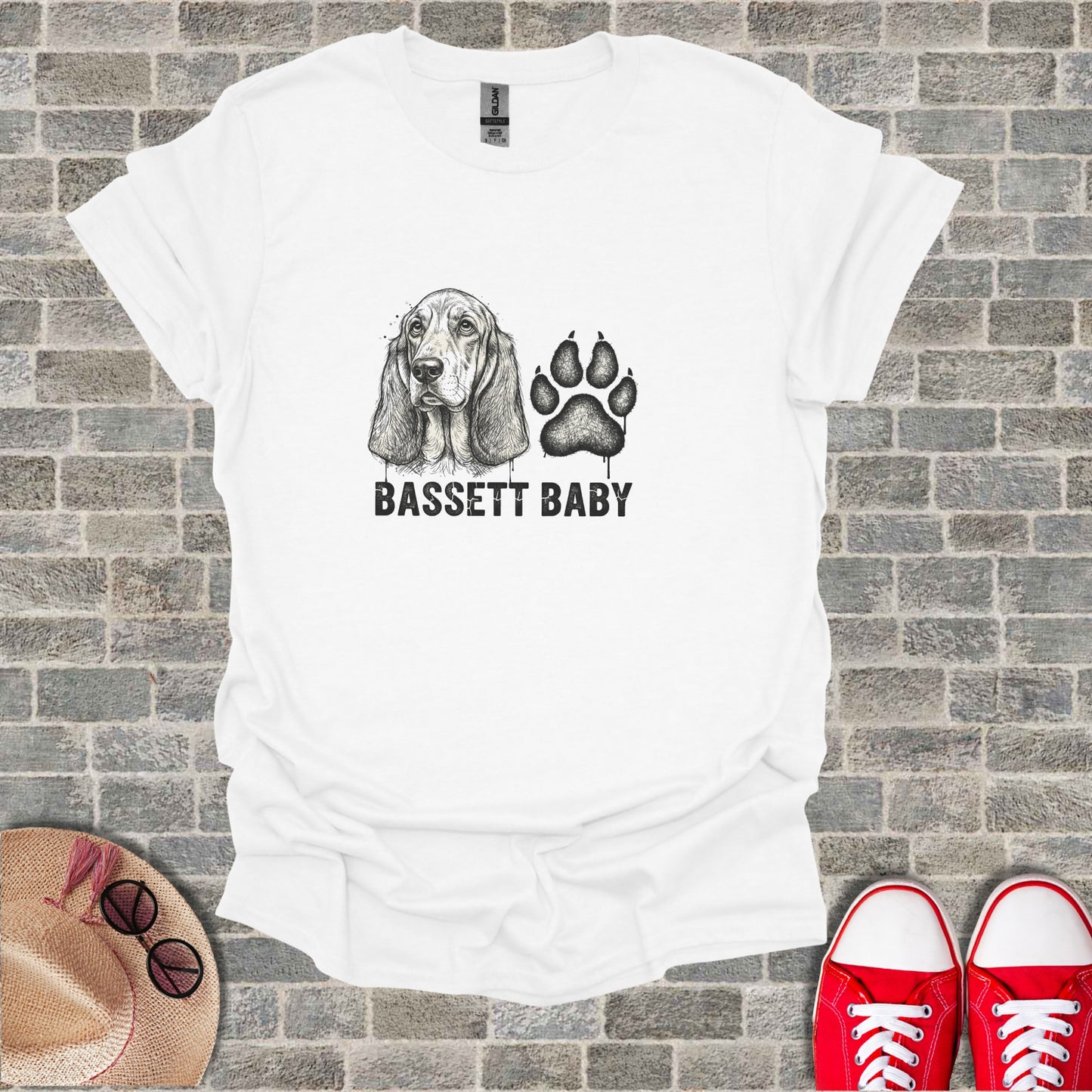White t-shirt with black ink drawing of a Basset Hound and paw print, text reads BASSETT BABY.