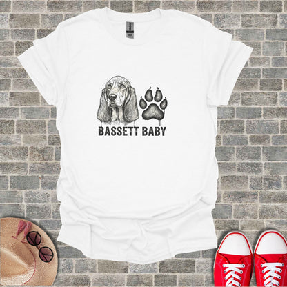 White t-shirt with black ink drawing of a Basset Hound and paw print, text reads BASSETT BABY.