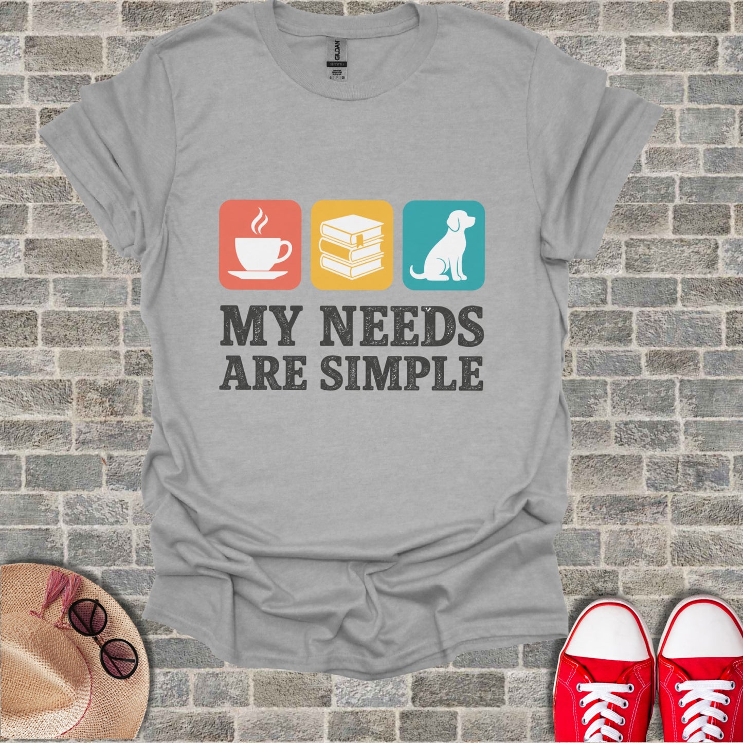 Grey t-shirt with coffee, books, and dog icons and text: "My needs are simple."
