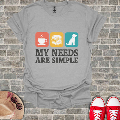 Grey t-shirt with coffee, books, and dog icons and text: "My needs are simple."