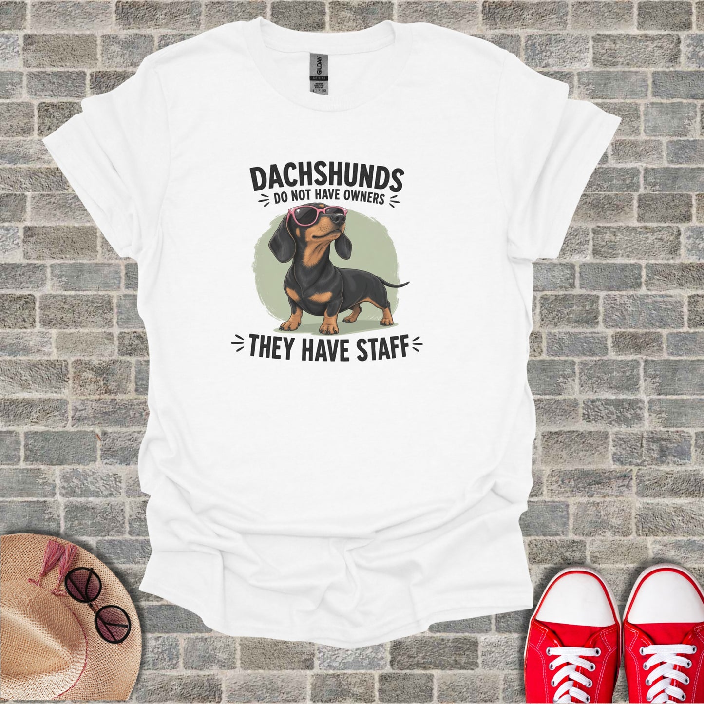 Dachshund wearing sunglasses, with text "Dachshunds do not have owners, they have staff".