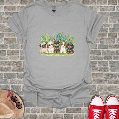 T-shirt with watercolor illustration of five puppies in front of green leaves.