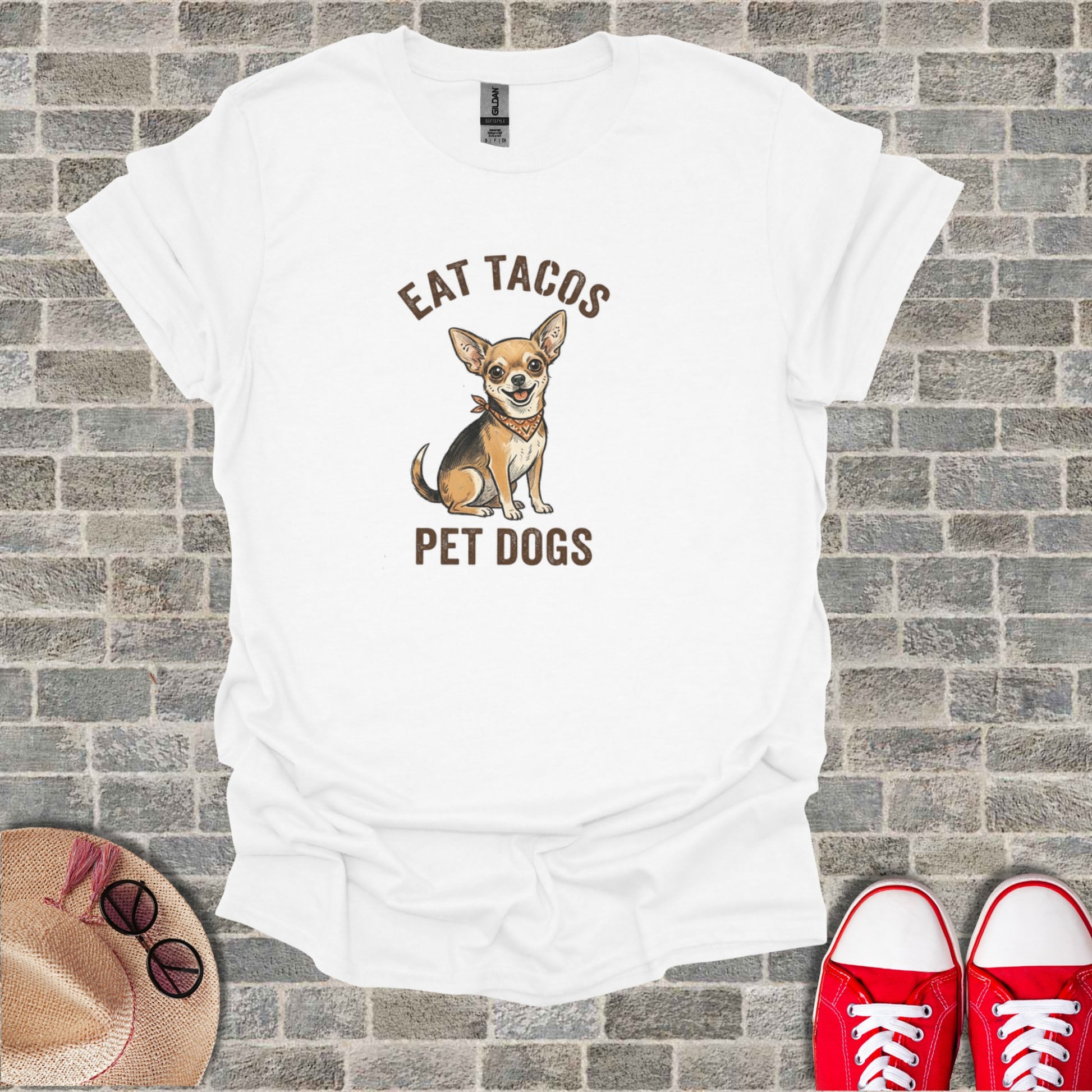 White t-shirt with a chihuahua wearing a bandana and text "EAT TACOS PET DOGS".
