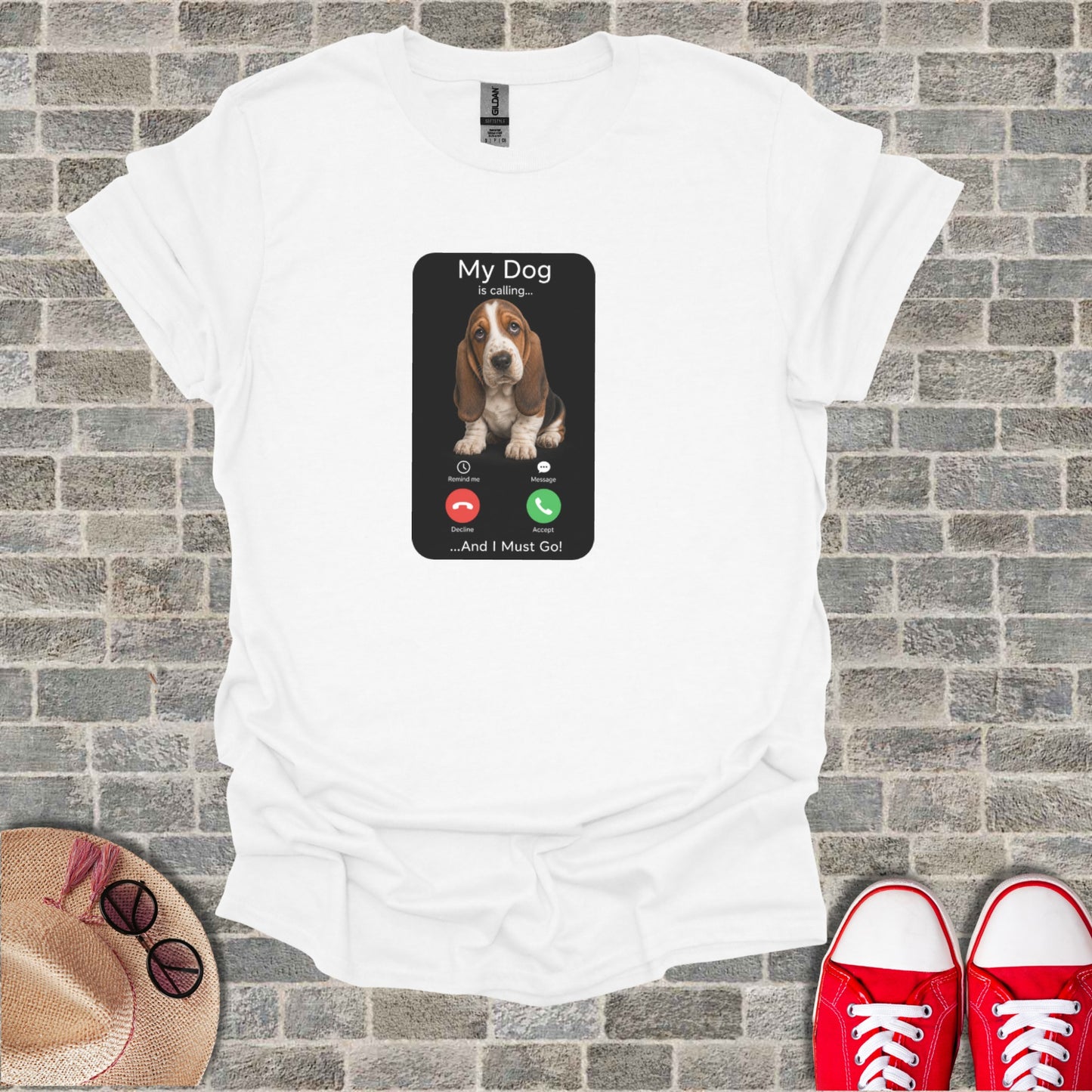 White t-shirt with a graphic of a phone screen showing a dog calling, text says "My Dog is calling... ...And I Must Go!"