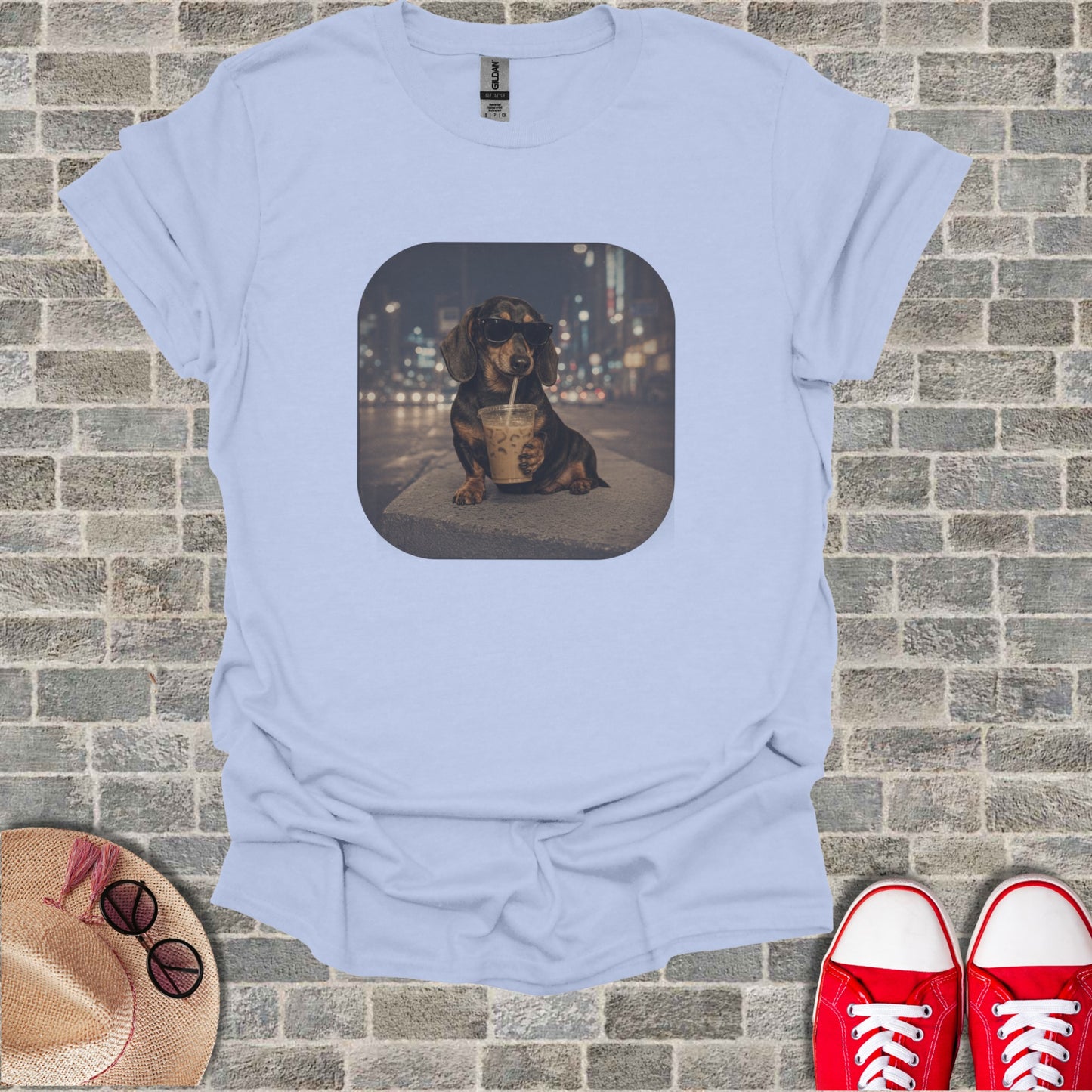 Dachshund wearing sunglasses drinks from a cup with city lights behind it.