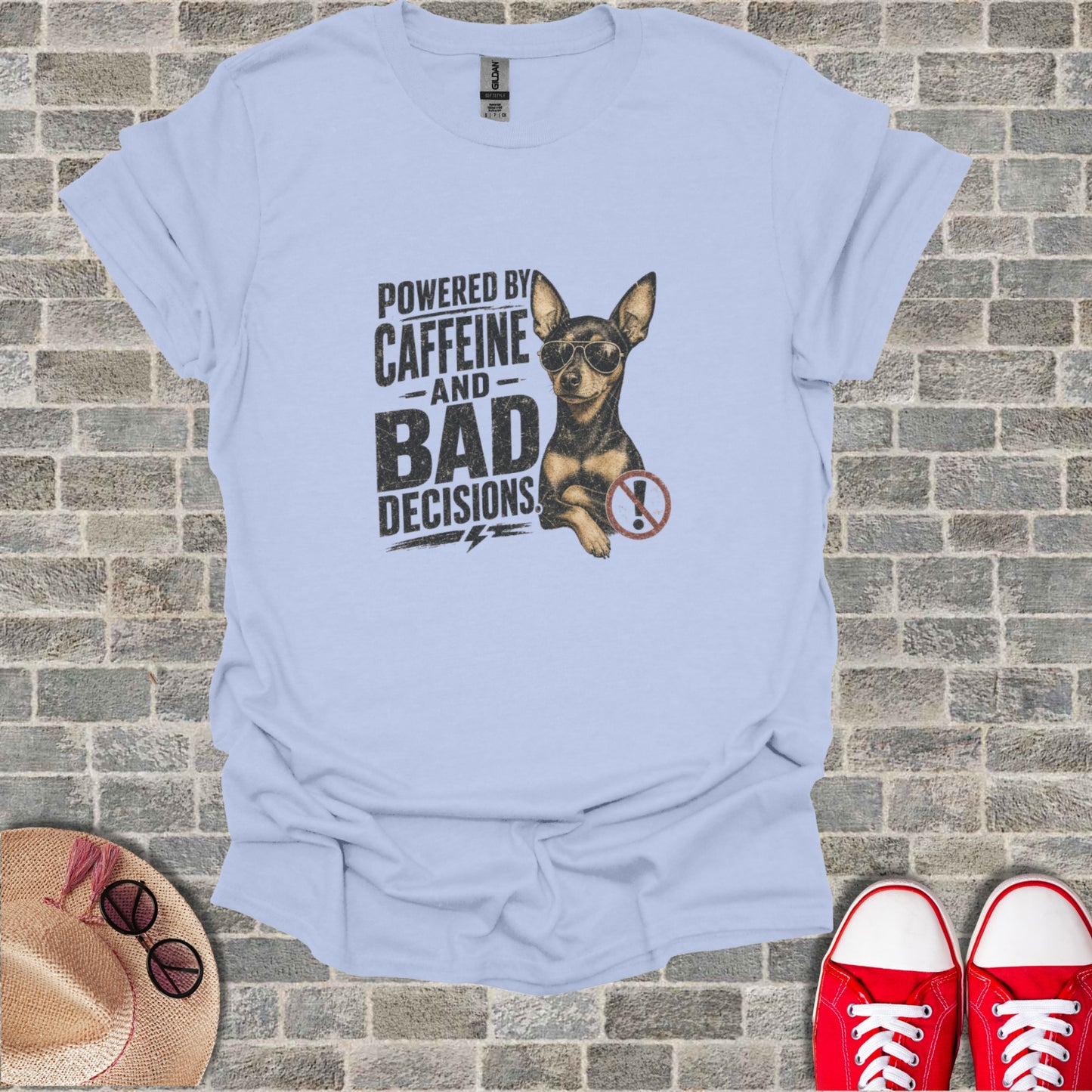 Light blue t-shirt with a chihuahua wearing sunglasses and text reading "Powered by Caffeine and Bad Decisions."