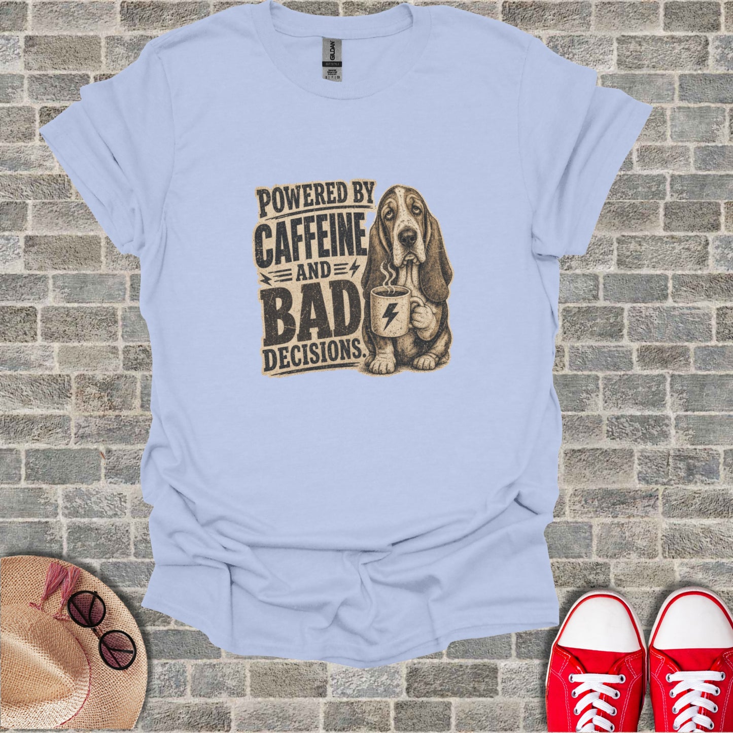 Light blue t-shirt with graphic of a basset hound holding coffee, text reads "Powered by Caffeine and Bad Decisions".