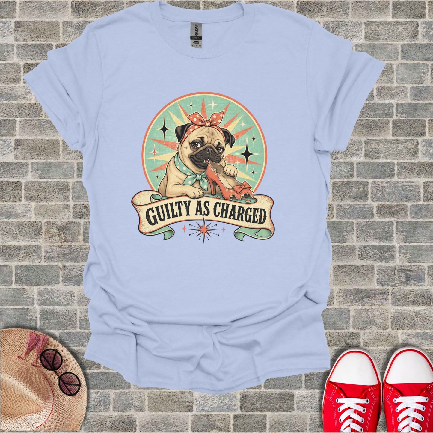 Light blue t-shirt with pug wearing bandana and eating a red heel, "Guilty as Charged" text.