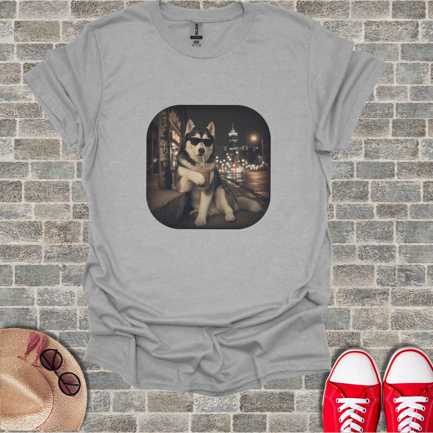Husky dog wearing sunglasses sits and drinks from a straw in front of city lights.